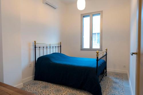 una camera da letto con un letto con un copriletto blu e una finestra di Chez Jojo a Port-Vendres