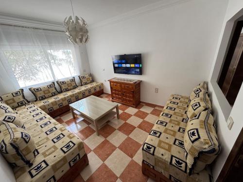 ein Wohnzimmer mit Sofas, Tisch und Fernseher in der Unterkunft My home in Tétouan
