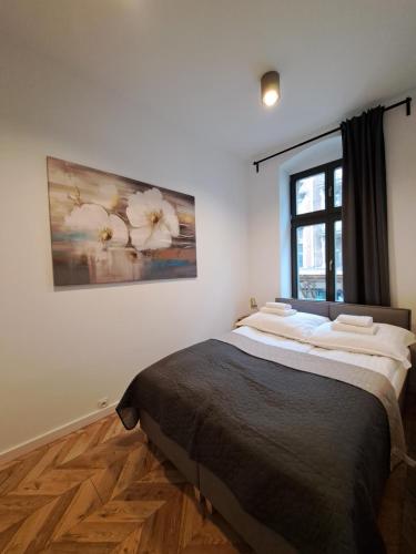 a bedroom with a bed with a painting on the wall at CanvasHome Apartamenty Aparthotel 250m od Rynku in Katowice