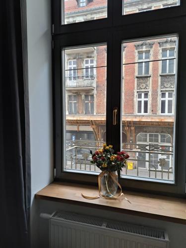 una finestra con un vaso di fiori sul davanzale di una finestra di CanvasHome Apartamenty a Katowice