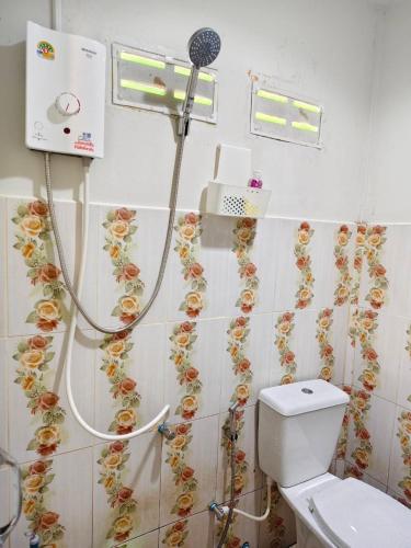 a bathroom with a shower and a toilet with flowers on the wall at TR Bungalow in Ban Tha Rua