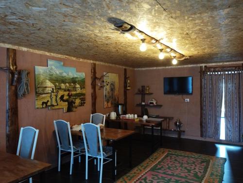 een eetkamer met een tafel, stoelen en een tv bij Arashan Guest house in Teploklyuchinskoye