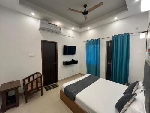 ein Schlafzimmer mit einem Bett, einem TV und blauen Vorhängen in der Unterkunft Ashoka Resort in Begusarai