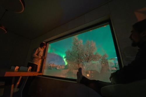 Ein Mann steht vor einem großen Fenster mit einem grünen Bildschirm in der Unterkunft Casa Hikari - Lofoten Retreat in Vestvågøya