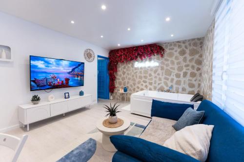 a living room with a blue couch and a tv at Évasion Santorin - Jacuzzi & Relax in Le Havre