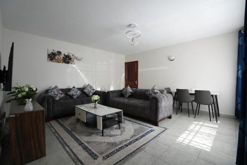 een woonkamer met twee banken en een tafel bij Modern Kisumu Apartment Near Airport, Malls & Lake Victoria in Kisumu