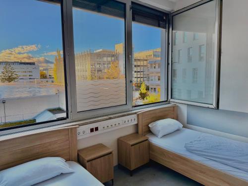 twee bedden in een kamer met twee ramen bij Haus an der Brücke in München