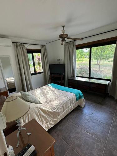 a bedroom with a bed and a desk and window at Las Cortaderas House in Trancas