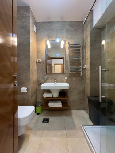 ein Badezimmer mit Waschbecken, Toilette und Spiegel in der Unterkunft Gorica Hill Luxury Residence in Podgorica