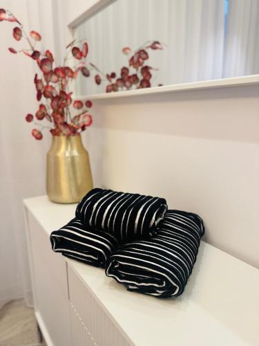three black and white pillows on a shelf with a vase at Pastello & Bianco in Biskupiec