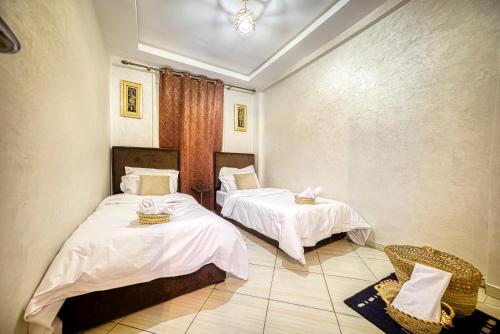 a room with two beds with white sheets at Appartement saada Agadir in Agadir