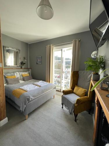 a bedroom with a bed and a chair and a window at Millpool House in Dartmouth