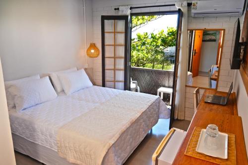 una camera da letto con un letto e una porta su un balcone di Pousada da Encosta a Garopaba