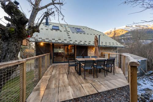 a wooden deck with a table and chairs on it at Chalet - Les Fermes de Céline - Barcelonnette in Enchastrayes