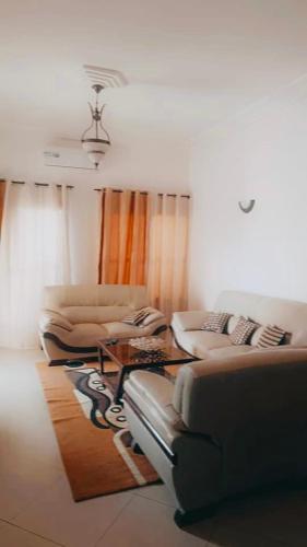 un soggiorno con due divani e un tavolo di Appartement Ode de paix a Cotonou Cadjehoun
