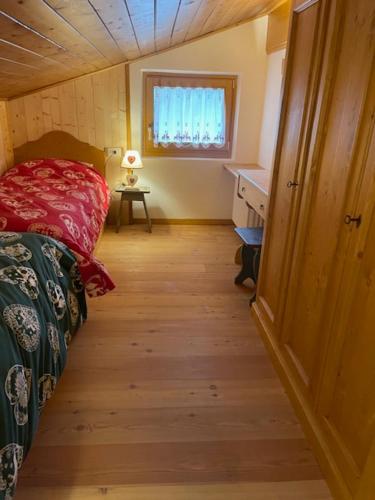 a small room with a bed and a table and a window at Chalet Luxury Pelmo in San Vito di Cadore