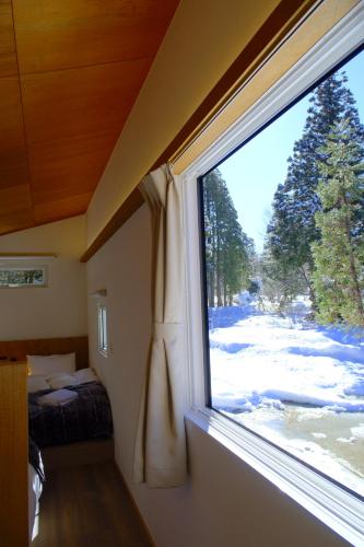 a window in a room with a bed and snow outside at 雪箱神楽 in Yuzawa