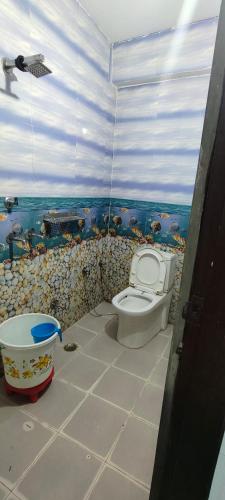 a bathroom with a toilet and a fish themed wall at Hotel Gloria Rishikesh in Rishīkesh