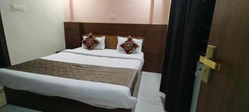 a bedroom with a bed with white sheets and pillows at Hotel Gloria Rishikesh in Rishīkesh