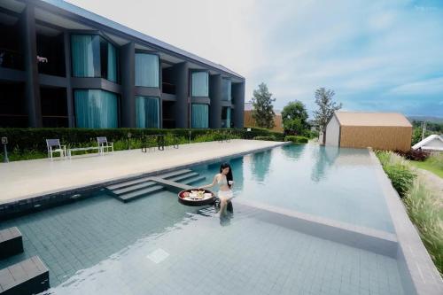 een vrouw in een zwembad naast een gebouw bij The Posh Khao Kho in Ban Nong Chaeng