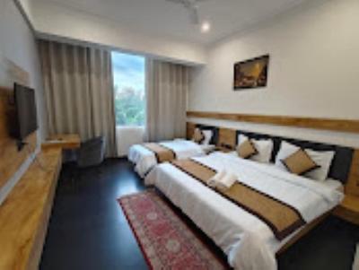 a hotel room with three beds and a flat screen tv at Hotel Basant Sarovar in Mathura