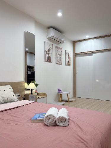 a bedroom with two towels on a pink bed at Homestay Nhà Thu Thu Vinhome Ocean Park in Gia Lâm Pho