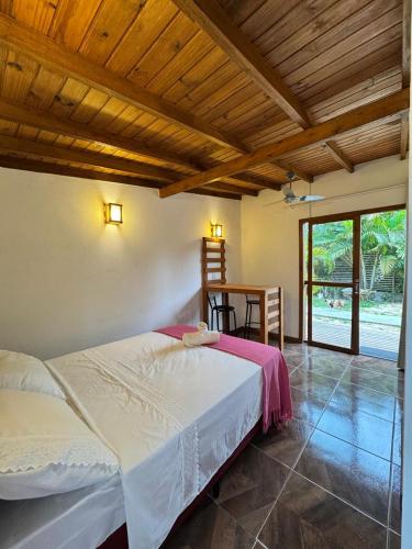 een slaapkamer met een wit bed en een houten plafond bij palmaresuites in Imbituba