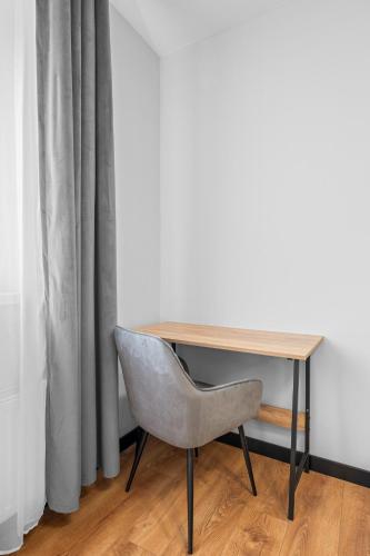 a desk with a chair next to a curtain at Centrum Prestige Apartments in Rybnik