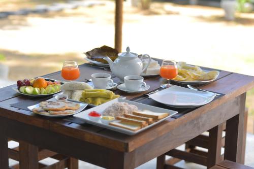 a wooden table topped with plates of food and drinks at Coco Villa Udawalawe in Udawalawe