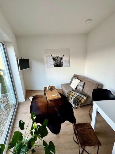 een woonkamer met een bank en een stierenkop aan de muur bij Moderne Ferienwohnung nahe Bostalsee in Nohfelden