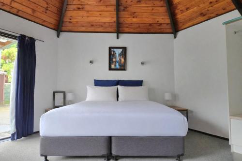 a bedroom with a large white bed with blue pillows at Pure Motel in Rotorua