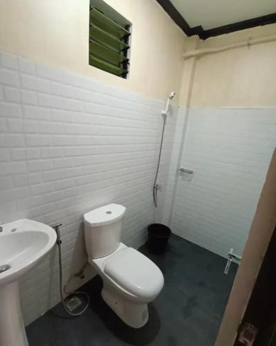 a bathroom with a white toilet and a sink at CocoVille Guesthouse Couple Room in Alegria