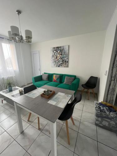 een woonkamer met een groene bank en een tafel bij Appartement Troyes in Troyes
