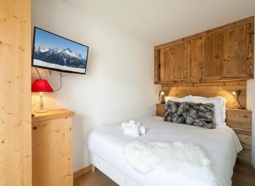 una camera da letto con un letto e una tv a parete di Melba Megeve emplacement de rêve dans le village au calme a Megève