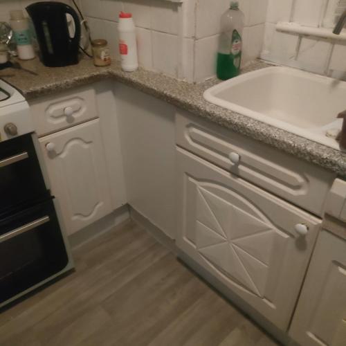 a white kitchen with a sink and a counter at Room2let in Moffat