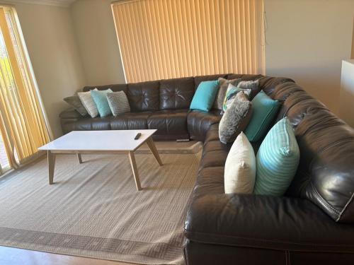 a living room with a leather couch and a coffee table at Bertram Family Retreat in Wellard