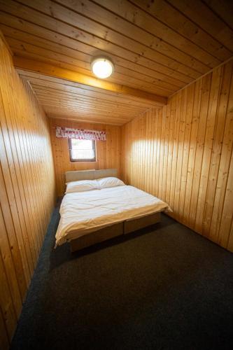 a room with a bed in a wooden cabin at Chata SKI Jezersko in Vígľaš