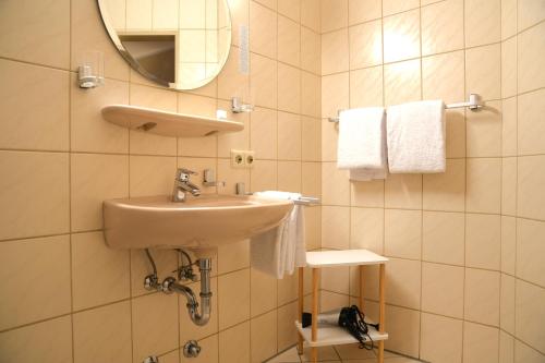 a bathroom with a sink and a mirror and towels at Hotel Bentheimer Eck in Bad Bentheim