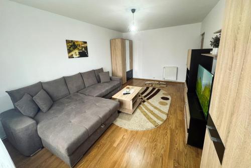 un soggiorno con divano grigio e TV di Edge Apartament a Cristuru Secuiesc