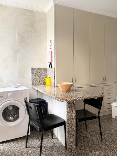 a kitchen with a counter with two chairs and a washing machine at BARRAMARES 3 in Furadouro