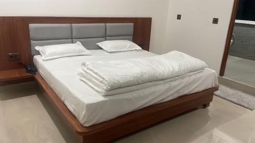 a bed with white sheets and pillows on it at Hotel HimNivasa in Tehri-Garhwāl