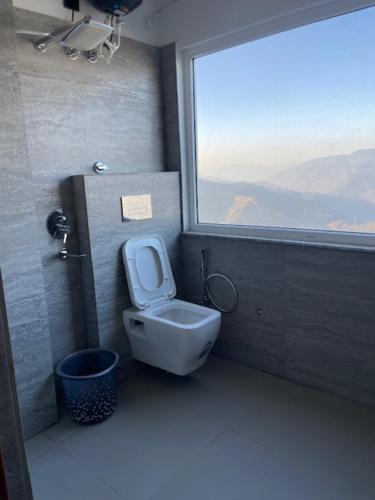 a bathroom with a toilet and a window at Hotel HimNivasa in Tehri-Garhwāl