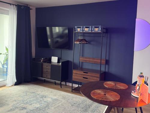 a living room with a table and a tv at CuxHeaven - modernes Studio-Apartment direkt am Meer mit Pool, Sauna und Massage in Cuxhaven