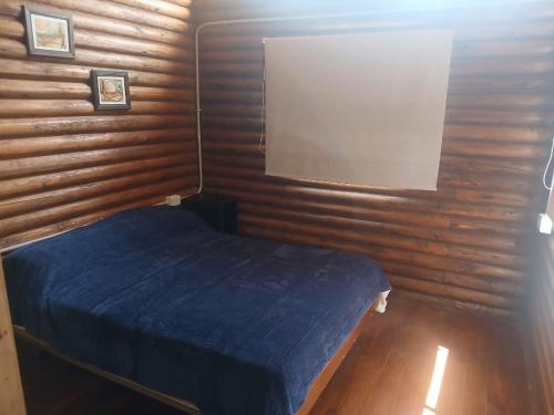 una camera con letto blu su una parete in legno di Cabaña Rincón del Aarón a Ciudad Lujan de Cuyo