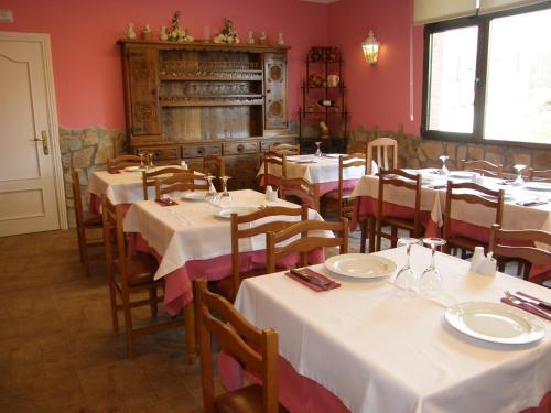 un comedor con mesas blancas y sillas de madera en Hotel Goizalde, en Sopelana
