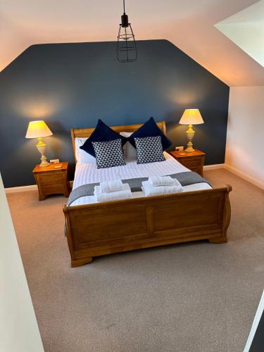 a bedroom with a large wooden bed with blue pillows at Hygge Homes - Modern 1 bed house in Lincoln