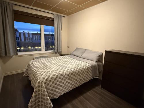 a small bedroom with a bed and a window at Apartement #4 avec chambre Baie Comeau in Baie-Comeau