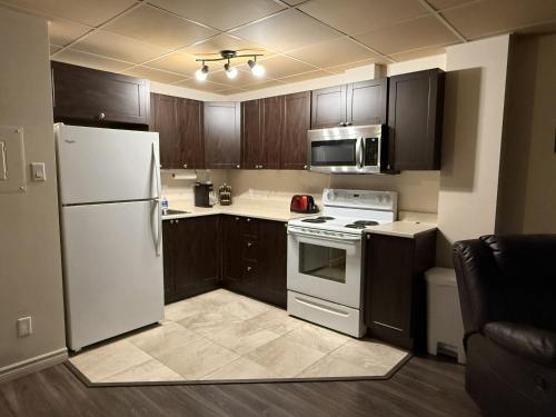 a kitchen with wooden cabinets and a white refrigerator at Apartement #4 avec chambre Baie Comeau in Baie-Comeau