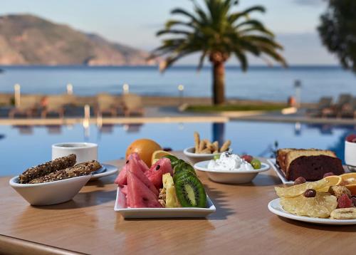 een tafel met borden eten op een tafel bij een zwembad bij Pilot Beach Resort in Georgioupolis