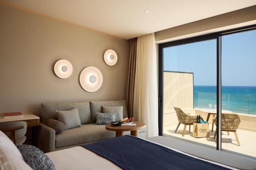 a bedroom with a bed and a couch and a balcony at Oros Luxury Beach Resort in Georgioupolis